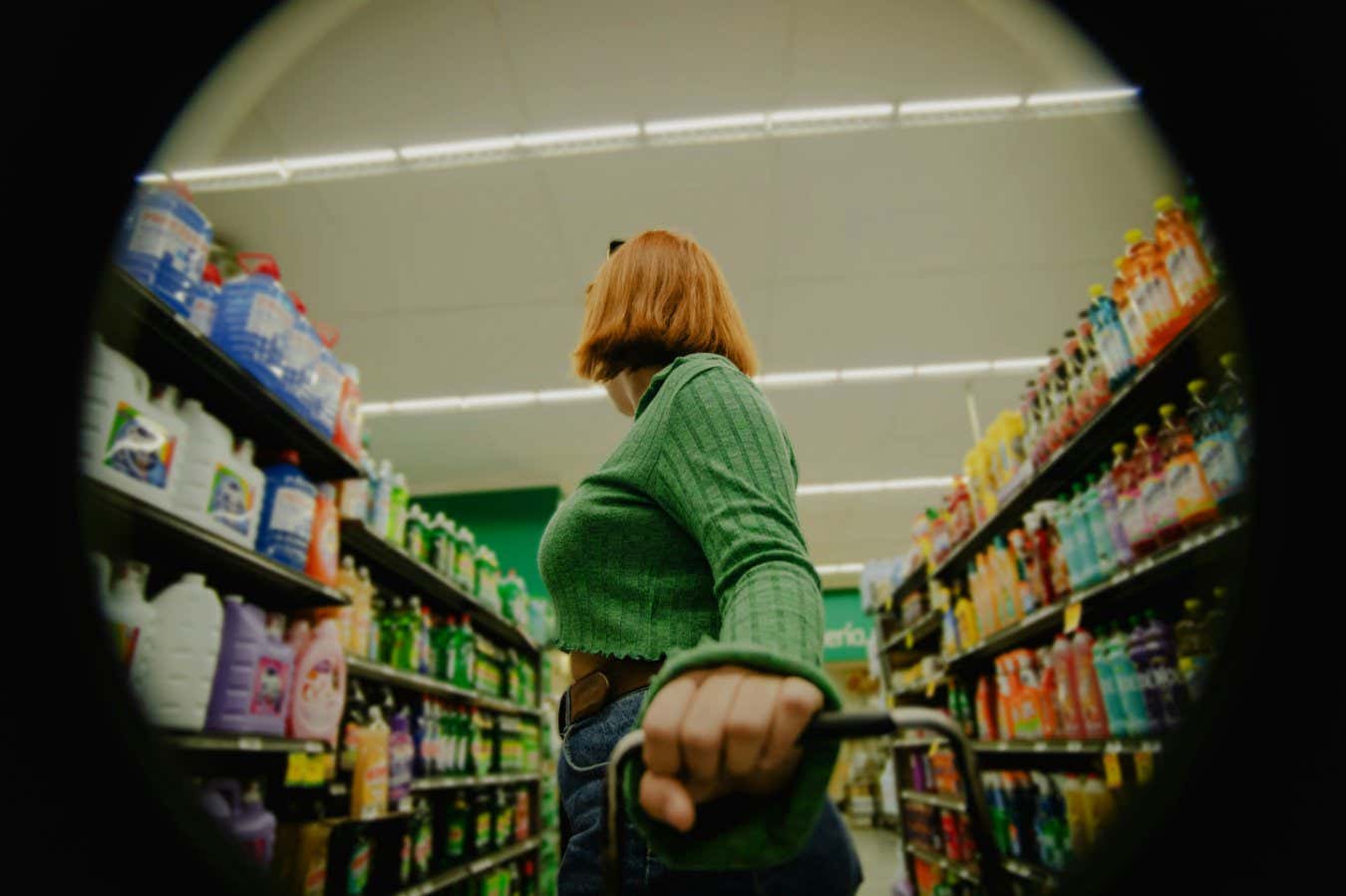 A woman in a green top surveys some supermarket ailes
