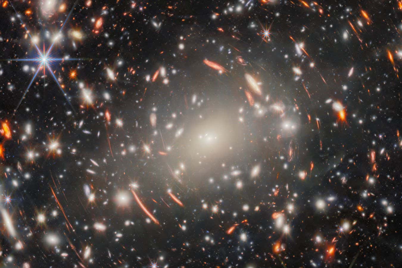 The eye is first drawn, in this new NASA/ESA/CSA James Webb Space Telescope Picture of the Month, to the central mega-monster that is galaxy cluster Abell S1063. This behemoth collection of galaxies, lying 4.5 billion light-years from Earth in the constellation Grus (the Crane), dominates the scene. Looking more closely, this dense collection of heavy galaxies is surrounded by glowing streaks of light, and these warped arcs are the true object of scientists??? interest: faint galaxies from the Universe???s distant past. Abell S1063 was previously observed by the NASA/ESA Hubble Space Telescope???s Frontier Fields programme. It is a strong gravitational lens: the galaxy cluster is so massive that the light of distant galaxies aligned behind it is bent around it, creating the warped arcs that we see here. Like a glass lens, it focuses the light from these faraway galaxies. The resulting images, albeit distorted, are both bright and magnified ??? enough to be observed and studied. This was the aim of Hubble???s observations, using the galaxy cluster as a magnifying glass to investigate the early Universe. The new imagery from Webb???s Near-Infrared Camera (NIRCam) takes this quest even further back in time. This image showcases an incredible forest of lensing arcs around Abell S1063, which reveal distorted background galaxies at a range of cosmic distances, along with a multitude of faint galaxies and previously unseen features. This image is what???s known as a deep field ??? a long exposure of a single area of the sky, collecting as much light as possible to draw out the most faint and distant galaxies that don???t appear in ordinary images. With 9 separate snapshots of different near-infrared wavelengths of light, totalling around 120 hours of observing time and aided by the magnifying effect of gravitational lensing, this is Webb???s deepest gaze on a single target to date. Focusing such observing power on a massive gravitational lens, like Abell S1063, therefore h